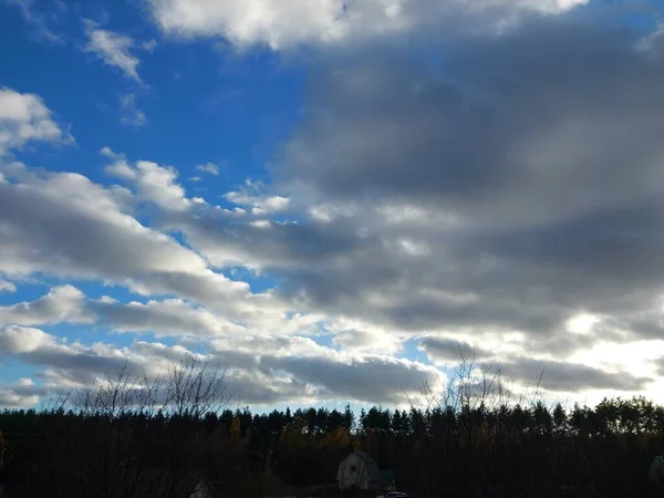 複数の色の雲が村の上を飛ぶ — ストック写真