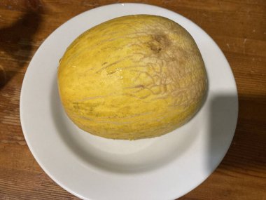 Beyaz tabakta olgun, sarı bir kavun
