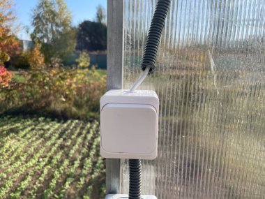 Bir seraya elektrik kablosu kurma sürecini yakalayan bir görüntü, aydınlatma, ısıtma ve ekipman için güç sağlıyor.