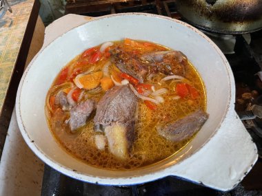 A chef prepares a rich veal stew, adding fresh vegetables and spices to a simmering pot. This image highlights the process of creating a warm and flavorful homemade dish, perfect for a cozy meal clipart