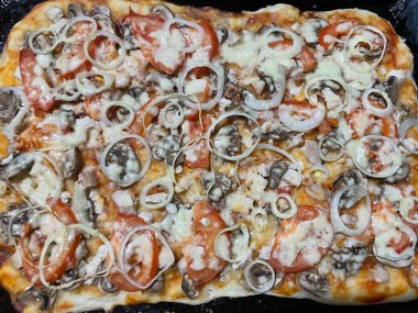 Taze pişmiş, altın kenarlı bir pizza, metal bir fırın tepsisinin üzerinde duruyor..