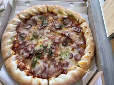 Klasik bir karton teslimat kutusuna yerleştirilmiş taze pişmiş pizza..