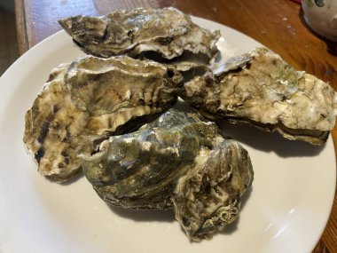 Ezilmiş buz üzerinde servis edilen taze çiğ istiridyeler, sıklıkla limon parçaları, otlar ve soslarla birlikte..