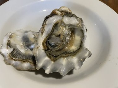 Ezilmiş buz üzerinde servis edilen taze çiğ istiridyeler, sıklıkla limon parçaları, otlar ve soslarla birlikte..