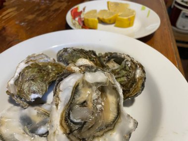 Ezilmiş buz üzerinde servis edilen taze çiğ istiridyeler, sıklıkla limon parçaları, otlar ve soslarla birlikte..