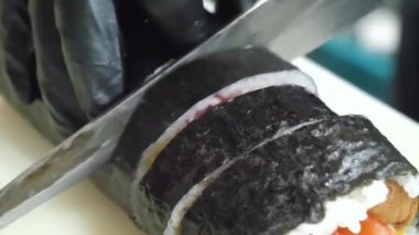 Sushi Senfonisi: Profesyonel Kesinlikte Nefis Rolls Rolls. Profesyonel bir şefin uzman elleri titizlikle pirinçten, somondan ve ton balıklı filetodan suşi yapar. Bitmiş başyapıtların zarif bir şekilde nasıl yapıldığını izleyin..