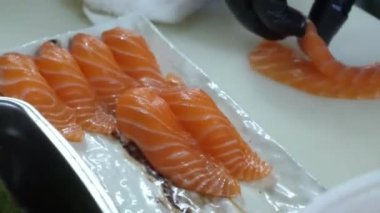 Sushi Senfonisi: Profesyonel Kesinlikte Nefis Rolls Rolls. Profesyonel bir şefin uzman elleri titizlikle pirinçten, somondan ve ton balıklı filetodan suşi yapar. Bitmiş başyapıtların zarif bir şekilde nasıl yapıldığını izleyin..