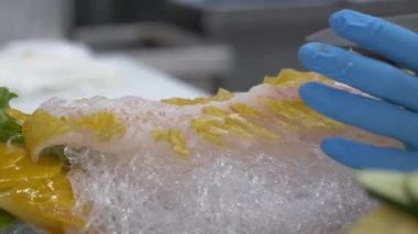 Işıl ışıl bir Japon balığını andıran altın pisi balığının yer aldığı görkemli bir yemek sahnenin ortasında yer alıyor. Lezzetli, şeffaf pirinç erişteleri balığın etrafına taşarken, canlı limon ve salatalık dilimleri görsel ve aşçılık deneyimini geliştirir..