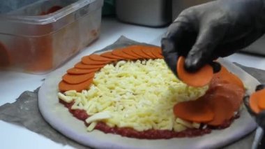 Üzerinde yabanmersini reçeli olan pizza hamuru ustalıkla şekillendirilmiş. Domates ezmesi, peynir ve sosis eklenir..