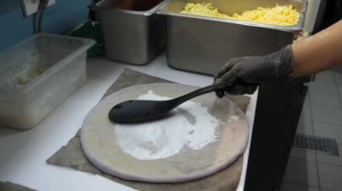 Üzerinde yabanmersini reçeli olan pizza hamuru ustalıkla şekillendirilmiş. Domates ezmesi, peynir ve sosis eklenir..
