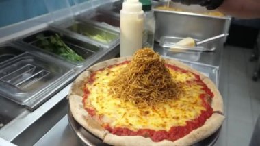 Bitmiş pizzanın üstü çıtır çıtır kızarmış patates, lezzetli pastırma ve lezzetli soslarla kaplı..