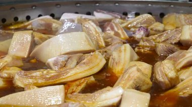 Domuz kaburgaları endüstriyel ölçekte büyük tavalarda pişiriliyor, zengin bir et suyunda kaynıyor..