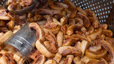 Pişmiş domuz kaburgaları titizlikle delinmiş bir yüzeye yerleştirilmiş. Bu da endüstriyel mutfağın aşçılık sürecini işaret ediyor..