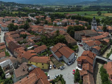 Slovenya 'nın Vipava şehrinin havadan görüntüsü. Arka plandaki Kızıl Çatı, Kilise, Tarla ve Orman Kaplı Tepeler