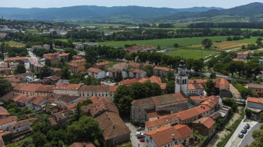 Slovenya 'nın Vipava şehrinin havadan görüntüsü. Arka plandaki Kızıl Çatı, Kilise, Tarla ve Orman Kaplı Tepeler