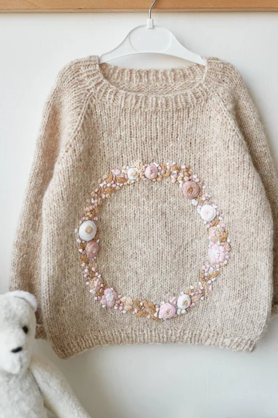 Baby knitted clothes. Handmade knitted sweater with flowers. Jacket with embroidery.