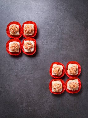 Top view of sushi roll pieces in paper pack. Four Sushi pieces with salmon on dark concrete background.