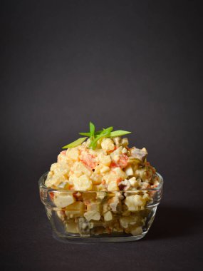 Olivier 'in cam kasede servis ettiği geleneksel Sovyet salatası. Patates ve havuç küplü salata, yeşil bezelye, salatalık turşusu, yeşil soğanlı yumurta. Karanlık arka plan. Yatay resim