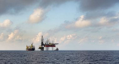 Sondaj kulesi ve FPSO gemisi açık deniz petrol sahasında güzel bulutlu mavi gökyüzü arkaplanıyla