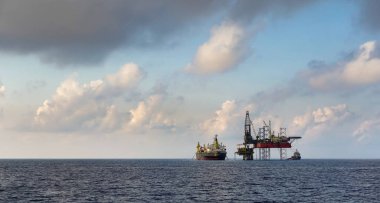 Sondaj kulesi ve FPSO gemisi açık deniz petrol sahasında güzel bulutlu mavi gökyüzü arkaplanıyla