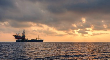 Kıyı açıklarında sondaj sondajı ve FPSO gemisi güzel bulutlu gün batımında altın saatler gökyüzü arka planında
