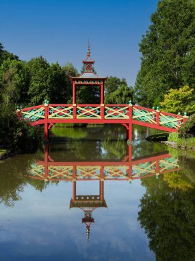 The Colourful Chinese Bridge at Park Floral D'Apremont over the lake in the parkland. clipart