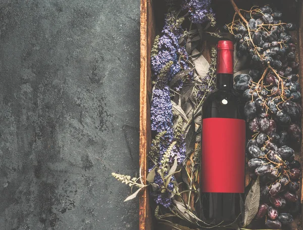 红葡萄酒瓶 红色空标签 仿制空间在木制盒子 葡萄和花在黑暗的混凝土厨房桌子上 乡村红酒的概念 顶部视图 — 图库照片