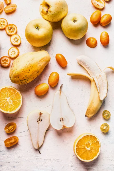 Various yellow and orange colors fruits flat lay on white desk, top view. Healthy food.