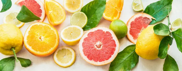 Various citrus fruits background banner with halves, slices and green leaves. Top view. Vitamin C. Healthy natural immun boosters. Refreshing ingredients for drinks