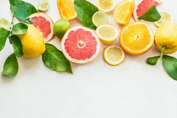 各种柑橘类水果与绿色叶子在白色背景的边界 顶部视图 一半的柑橘维生素C 健康的天然免疫助推器 — 图库照片