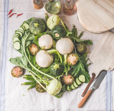 Masada bir yığın yeşil sebze: yeşil bezelye, kohlrabi, marul, kabak, salatalık, yeşil domates. Üst Manzara. Temiz vejetaryen yeme ve pişirme konsepti. Çiftlik yerel sebzeleri