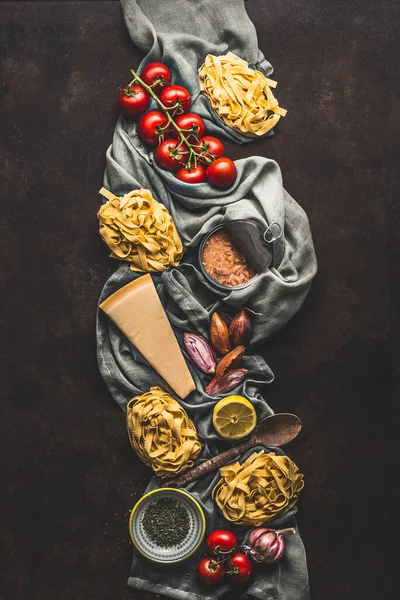 Tuna pasta cooking ingredients on dark rustic background, top view. Grocery products of Italian cuisine. Italian food. Caned tuna. Vertical. Flat lay