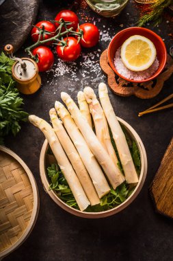 Bambu buharlı kuşkonmaz koyu kırsal mutfak masasında malzemeler ve çubuklarla, üst manzara. Sağlıklı beslenme ve mevsimsel pişirme. Asya yemekleri.