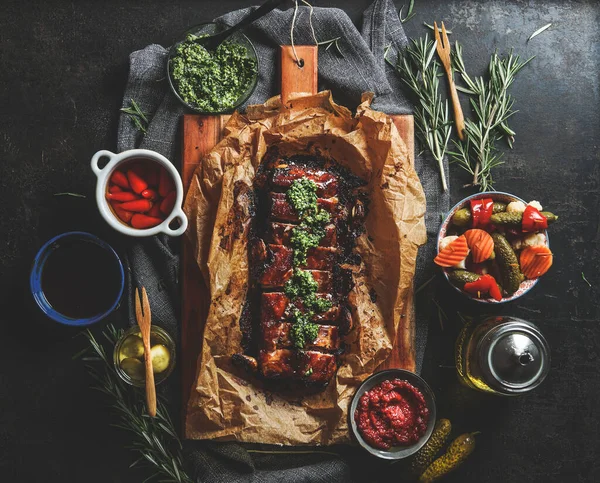自家製ペスト ソース ローズマリーをダークコンクリートのキッチンテーブルでローストしたバーベキューリブ 夕食においしい味付けの肉 トップ表示 ロイヤリティフリーのストック写真