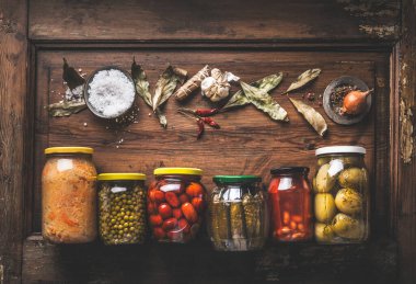 Ahşap zemin üzerinde konserve sebze kavanozları ve kurutulmuş baharatla birlikte yiyecek arka planı. Bahçe hasat kamışı. Ev yemekleri. Mayalanmış yiyecek. Sebze stoku. Çerçeve. Düz yatıyordu