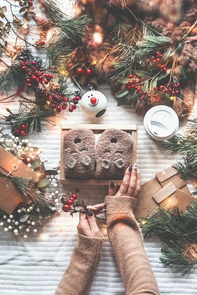 冬の装飾 松の枝 妖精の光とクラフト紙のカードと白い毛布の上に面白い手作りテディベアの靴下と女性の手を保持ボックス クリスマスプレゼント包装準備 ストックフォト