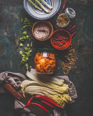 Fermented food and preserving concept. Glass with kimchi cabbage in jar on dark background with ingredients. Top view. Healthy food