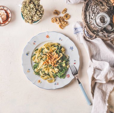 Healthy vegan lunch. Plate with tagliatelle noodles , spinach and roasted walnuts on light kitchen table background , top view