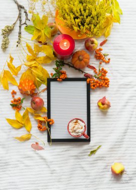 Sonbahar yaşam tarzı, boş mektup tahtasıyla, sıcak çikolata, yanan mum, balkabağı ve sarı yapraklarla yatıyordu. Üst Manzara. Rahat bir ev. Sonbahar moda konsepti