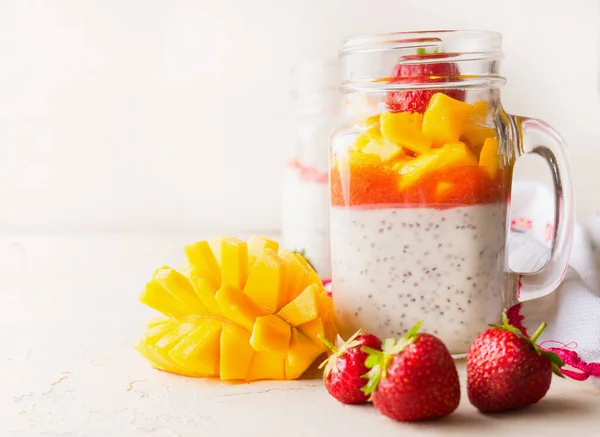 关闭玻璃瓶与奇亚种子酸奶布丁 芒果和草莓在白桌子上 复制空间 健康的素食早餐 — 图库照片