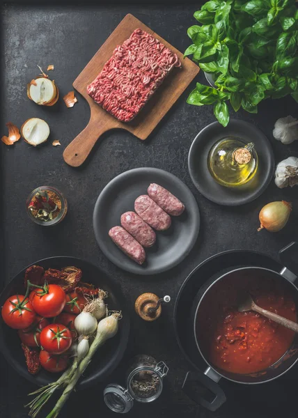 ソースボロネーゼのための様々な成分 Salsicciaソーセージ ミンチ肉 トマトソース 暗いキッチンの背景にハーブやスパイス 最上階だ 調理準備 — ストック写真