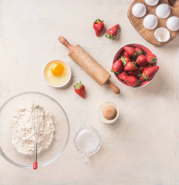 Un, yumurta, merdane ve çilekli fırın arka planı beyaz mutfak masası arka planı, üst manzara. Düz yatıyordu. Tatlı yemek. Pişirme malzemeleri ve aletler. Mevsimlik mutfak