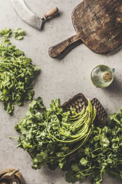 Mutfak masasında tahta kesim tahtası ve ot bıçağıyla taze maydanoz. Evde sağlıklı ve lezzetli malzemelerle yemek pişirmek. Üst görünüm.
