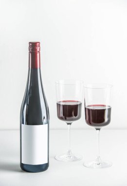 Kırmızı şarap seti ve beyaz arka planda iki şarap bardağı. Kopyalama alanı ile ön görünüm.