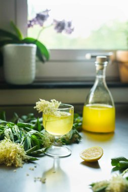 Elderflower Cordial 'lı cam şişeli ve malzemeli. Limonlu ferahlatıcı içecek. Ön görünüm