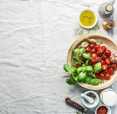 Mutfak masasının üzerinde domates ve fesleğen. Kremalı domates çorbasının sağlıklı pişirilmesi için gerekli malzemeler, üst manzara. Kenarlık