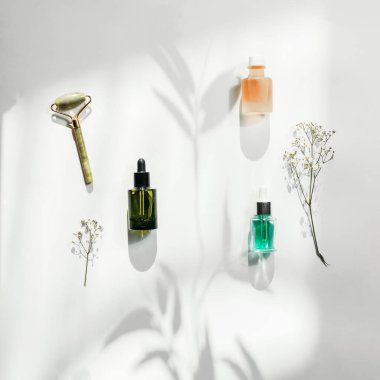 Beyaz arka planda güneş ışığı ve gölgeyle modern cilt bakımı kozmetiği. Güzellik ürünleri.