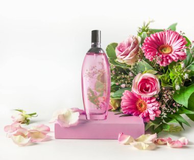 Kürsüde pembe parfüm şişesi ve beyaz arka planda güzel bir çiçek. Ön görünüm