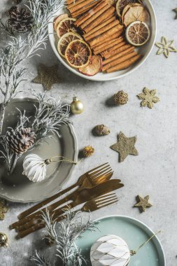 Noel sofrası dekorasyonu, tabaklar, çatal bıçak takımı ve kış baharatları: tarçın çubukları, anason yıldızları ve kuru portakal dilimleri, üst manzara