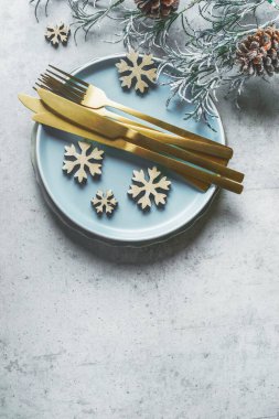 Altın çatal bıçak seti, mavi tabak ve kar taneleri süslemesi, üst manzara.